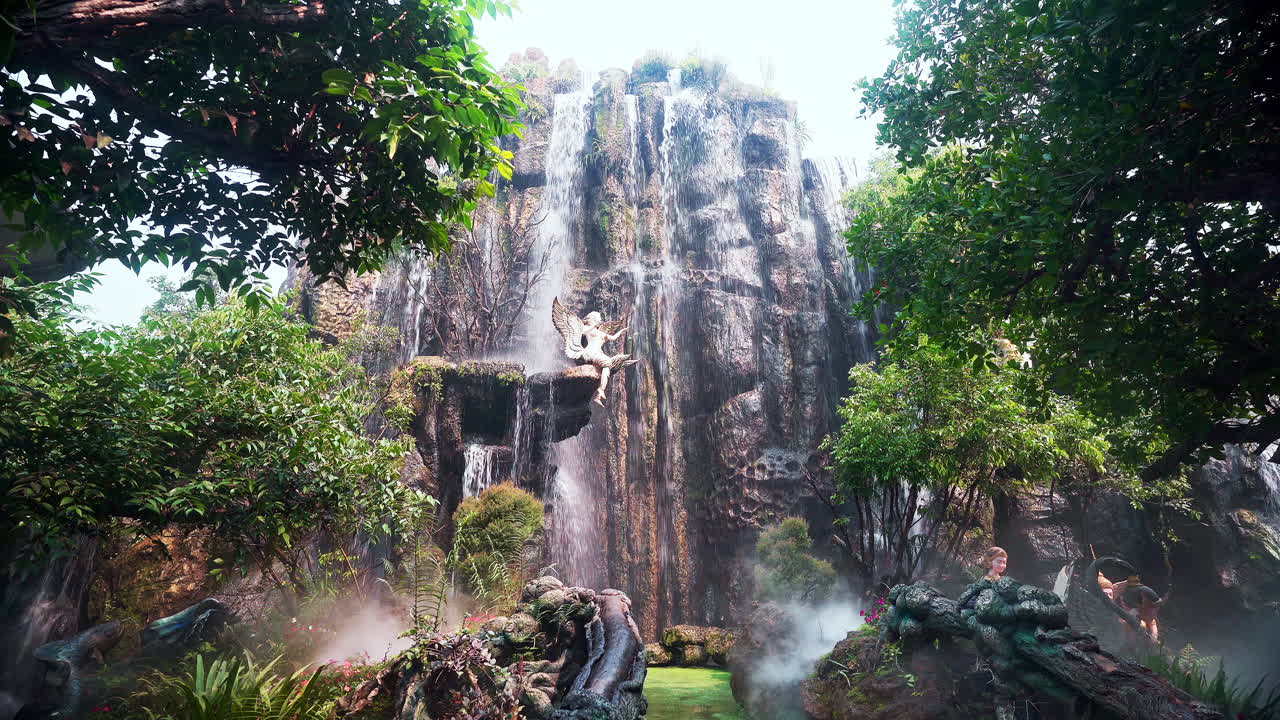 천사 동상 이 있는 열대 정원 에 있는 다리 위 에 있는 폭포 를 돌진 하고 있다