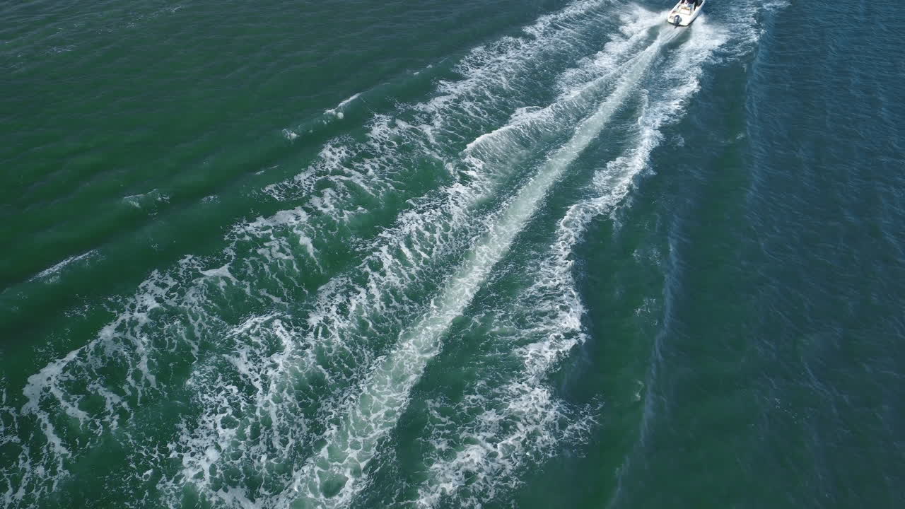 Motorboat speeding through the calm sea of ​​a lagoon. Sea waves as a tourist boat passes by.