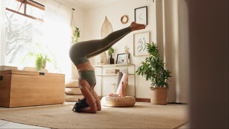 mujer realizando una postura de yoga de pie en la cabeza en casa