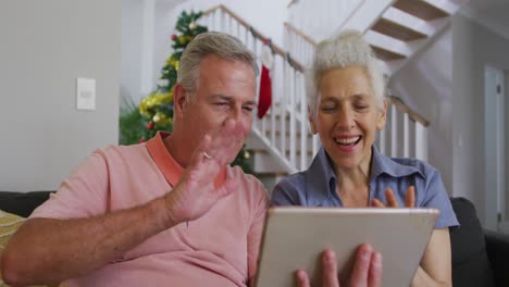 feliz pareja de adultos mayores caucásicos teniendo una videollamada en tiempo de navidad