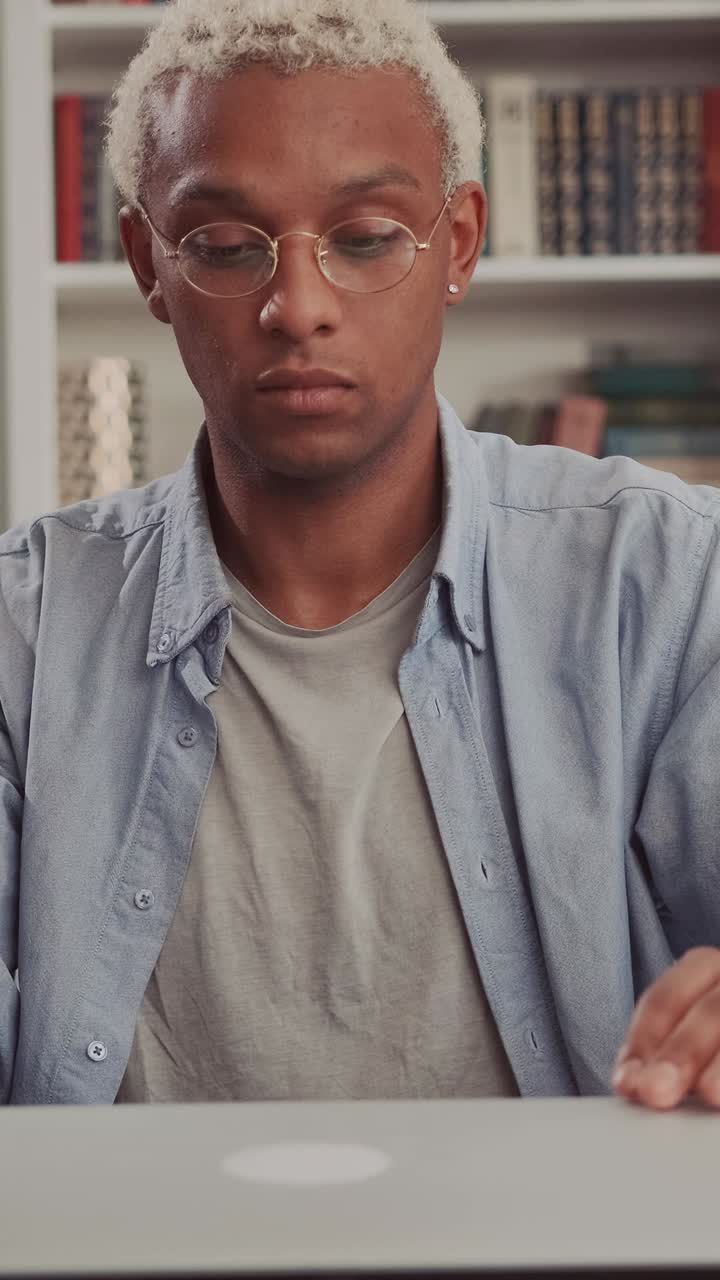Focused african american male studying at desk with laptop and books