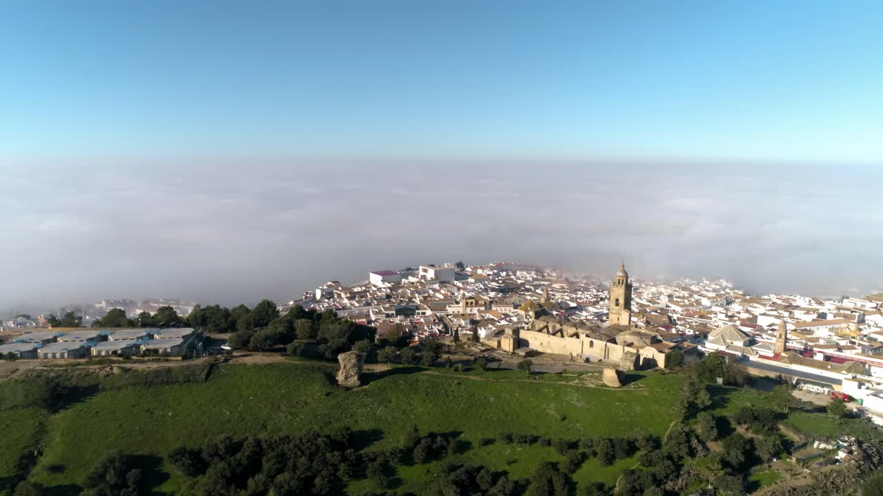 Carrellata aerea sul paesaggio di fronte a Medina Sidonia in Andalusia, Spagna, con vista sulla chiesa di Santa Maria e il bellissimo centro storico, con nuvole e cielo blu