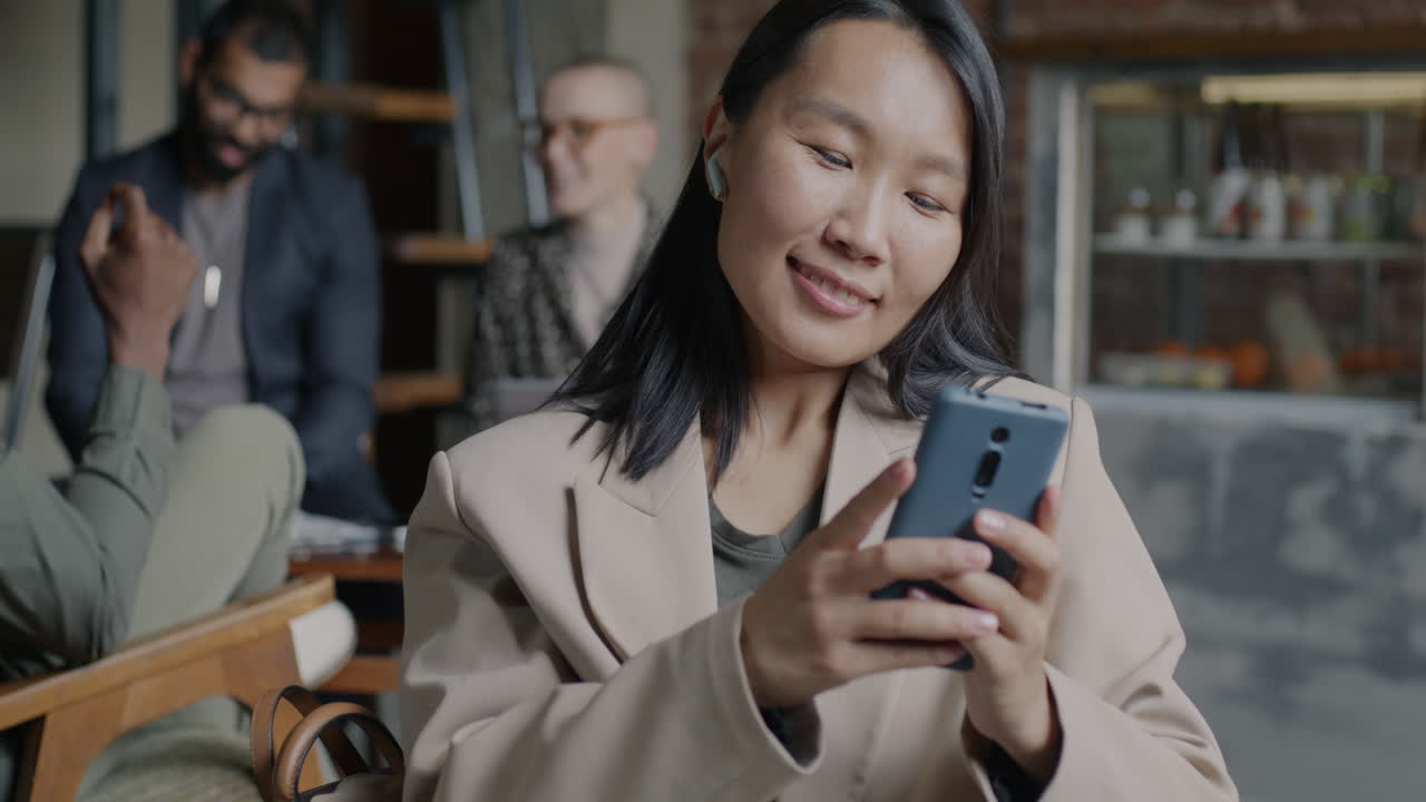 Woman using phone in a cafe with friends