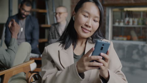 woman using phone in a cafe with friends