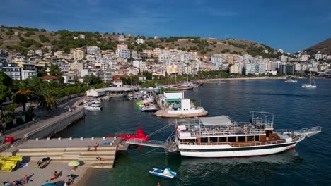 tranquil pier along saranda's coastal city, boats and tour ships anchored in the blue bay for summer leisure