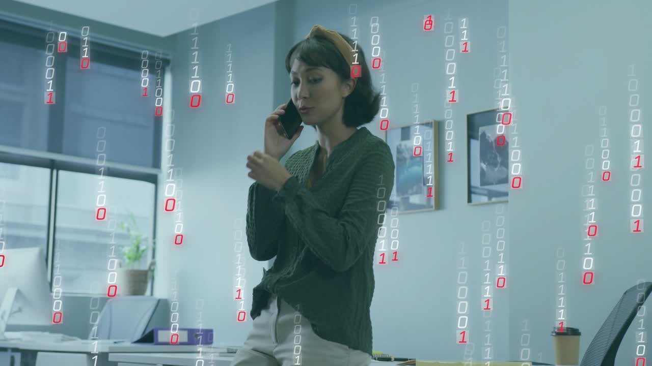 Office worker speaking on smartphone at desk, binary digits rising around her during business call