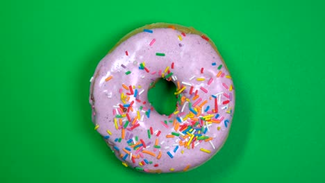 delicioso y fresco rosquilla de rosquilla macro disparo de primer plano girando sobre un fondo verde.