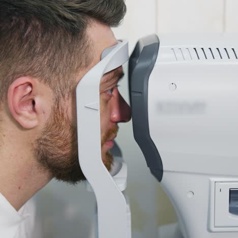 patient man looks at device in ophthalmology clinic. profile of patient's face looking into apparatus for eyes diagnostic in clinic. close-up
