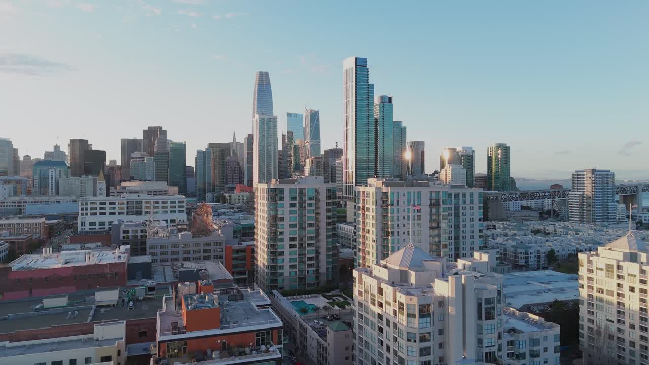 Drone ascends over water and rises from a coastal hillside to reveal San Francisco’s skyline, focusing on the Financial District dominating the historic urban core