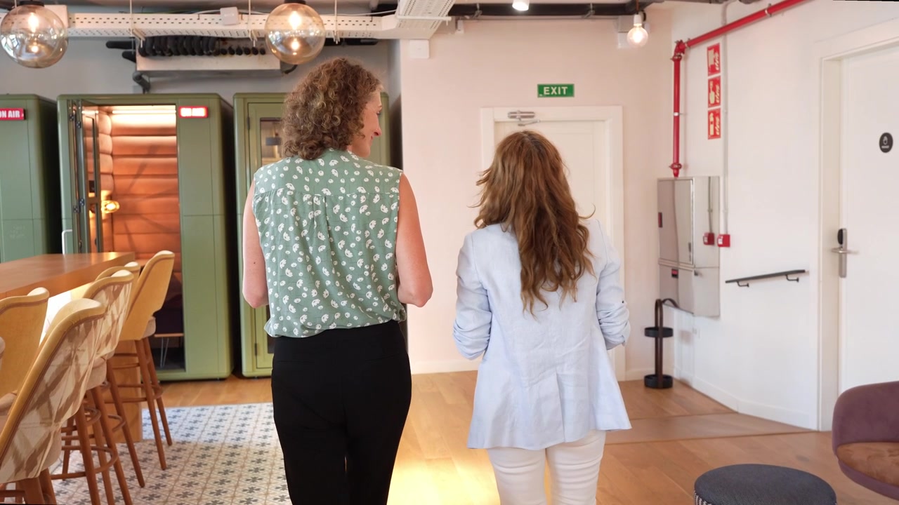 Two Businesswomen Walking and Talking in Modern Office