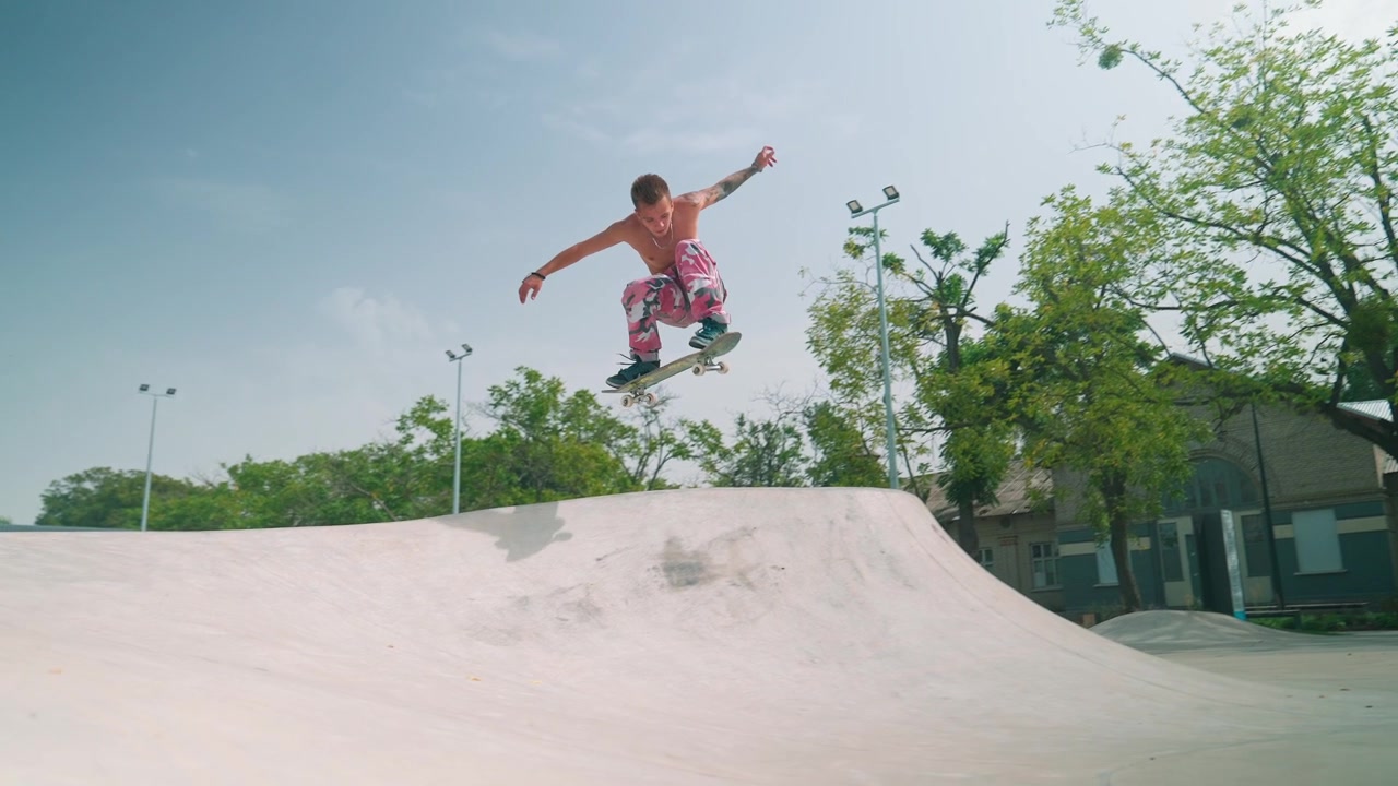 Skater uten skjorte hopper av rampe i sakte film.
