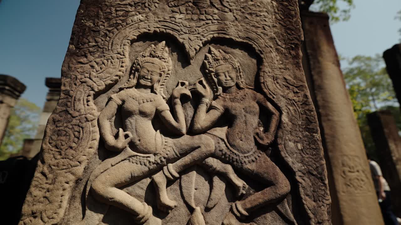 Yksityiskohtainen kivikaiverrus kahdesta khmer-hahmosta peilikuvamaisessa asennossa muinaisessa temppelissä Siem Reapissa, Kambodžassa