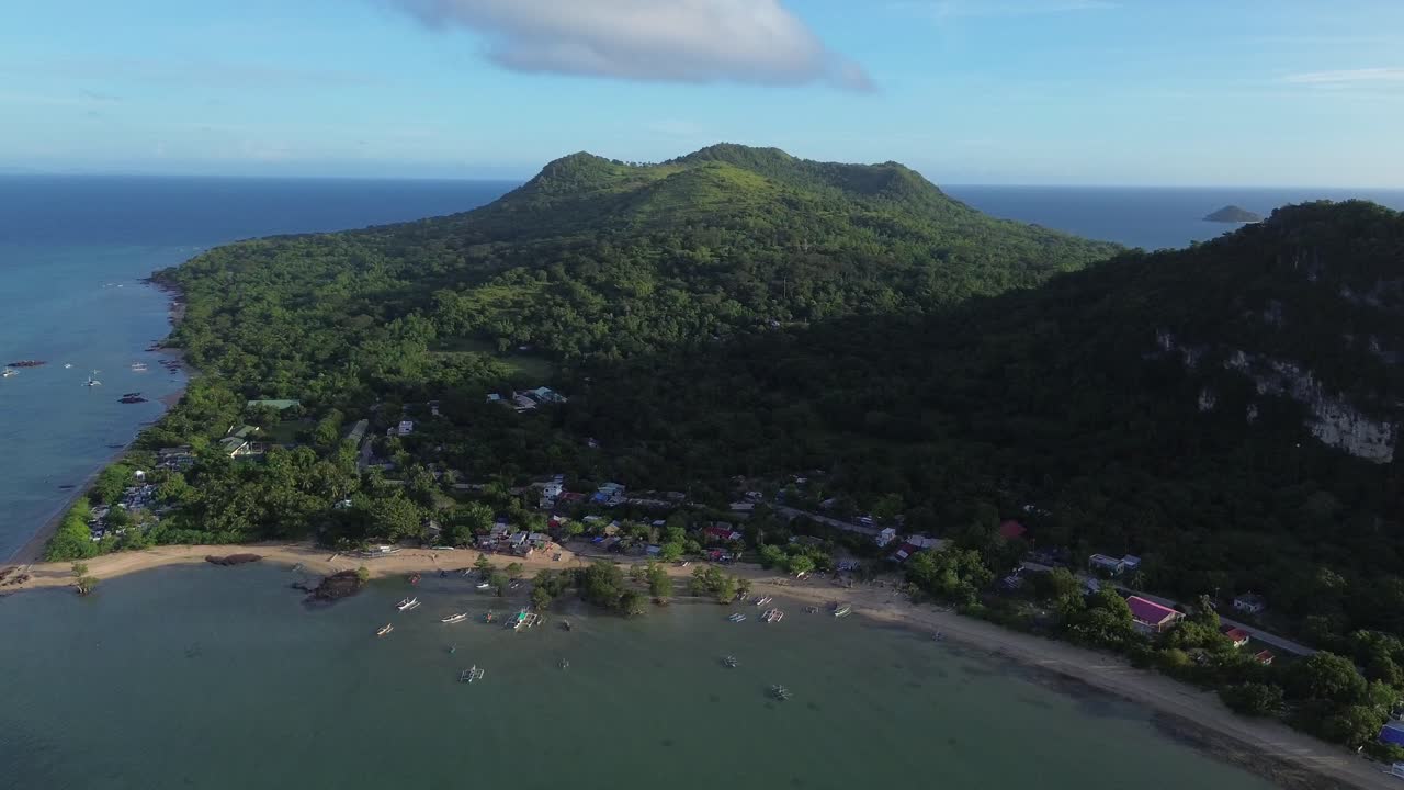 Vista aérea de dron a gran altitud de frondosas montañas verdes que cubren la isla Guimaras, Filipinas. Paisaje tropical remoto con densa vegetación y unas pocas casas pequeñas rodeadas de naturaleza virgen.