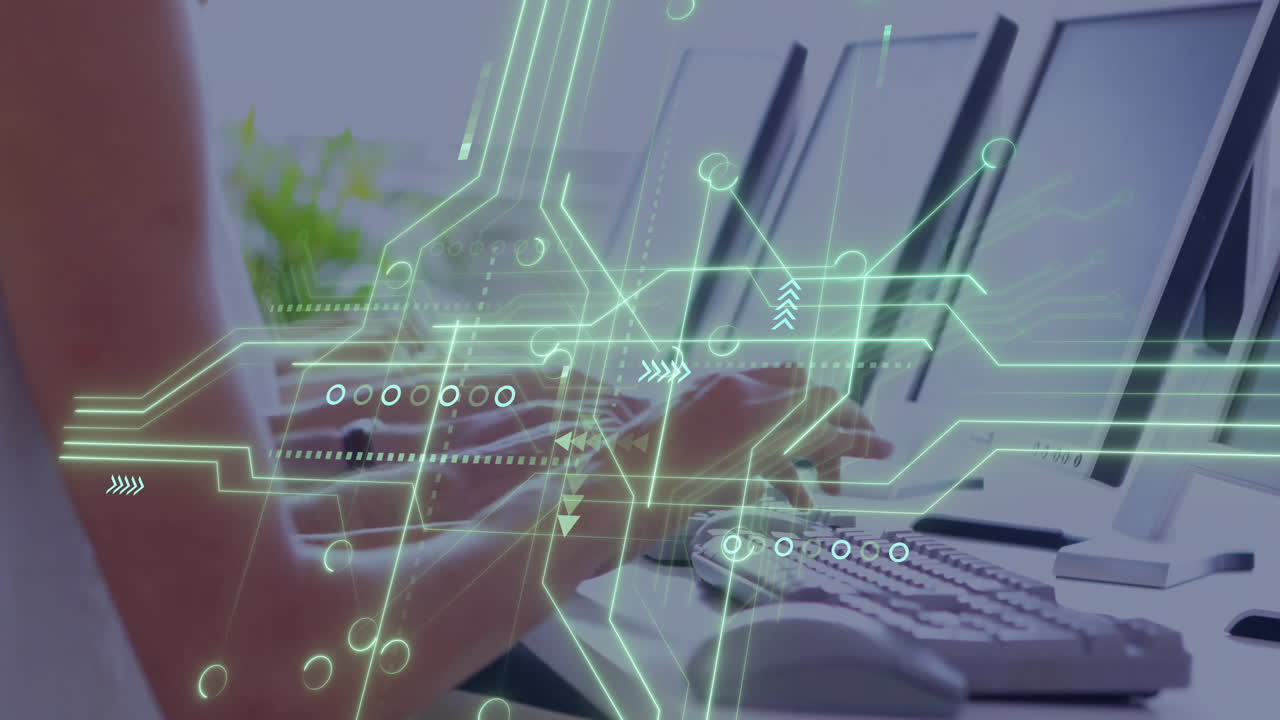 Hands and forearms typing on keyboard as green circuit graphics overlaying modern office workspace