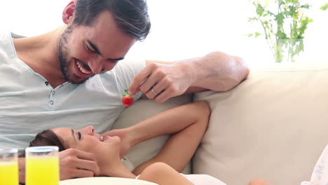 pareja atractiva comiendo fresas en el sofá