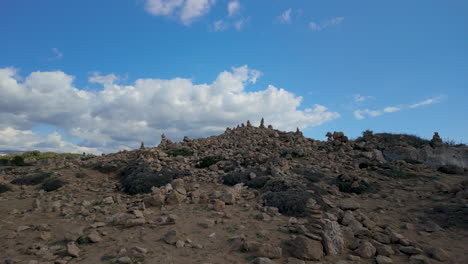 una colina escarpada y rocosa cubierta de piedras apiladas en las tumbas de los reyes en pafos