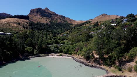 tracking and panning aerial shot of pretty bay with pine trees and rocky mountain in background