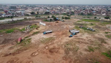 Aeriel-shot-of-an-open-space-garage-or-lorry-park-in-a-sparsely-populated-area-near-a-river