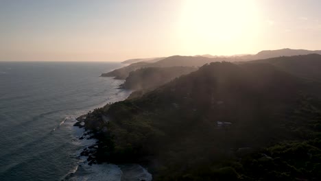 picturesque aerial shot of coastline alongside cliffside with pacific ocean water following the sun rays during sunset