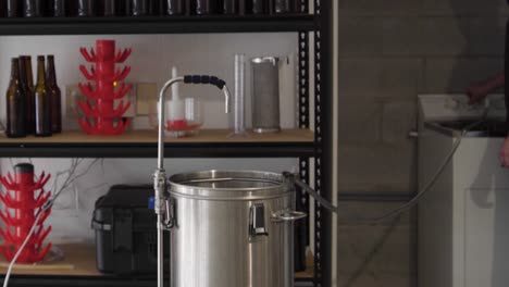 llenar una tetera de cerveza de metal con agua de una manguera en una cervecería artesanal casera