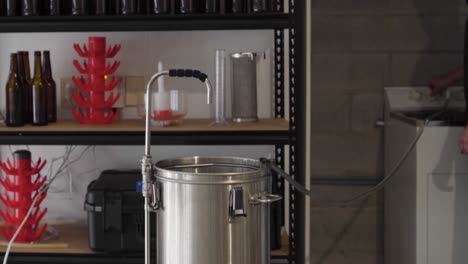 filling a metal brewing kettle with water from a hose in a home craft brewery