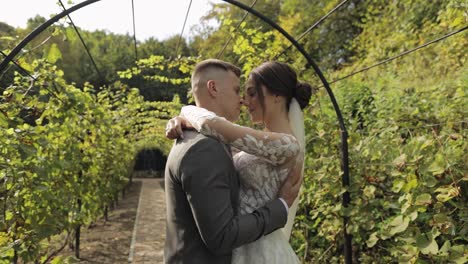 Lovely-newlyweds-caucasian-bride-embracing-groom-in-park-making-kiss,-wedding-couple-family-hugging