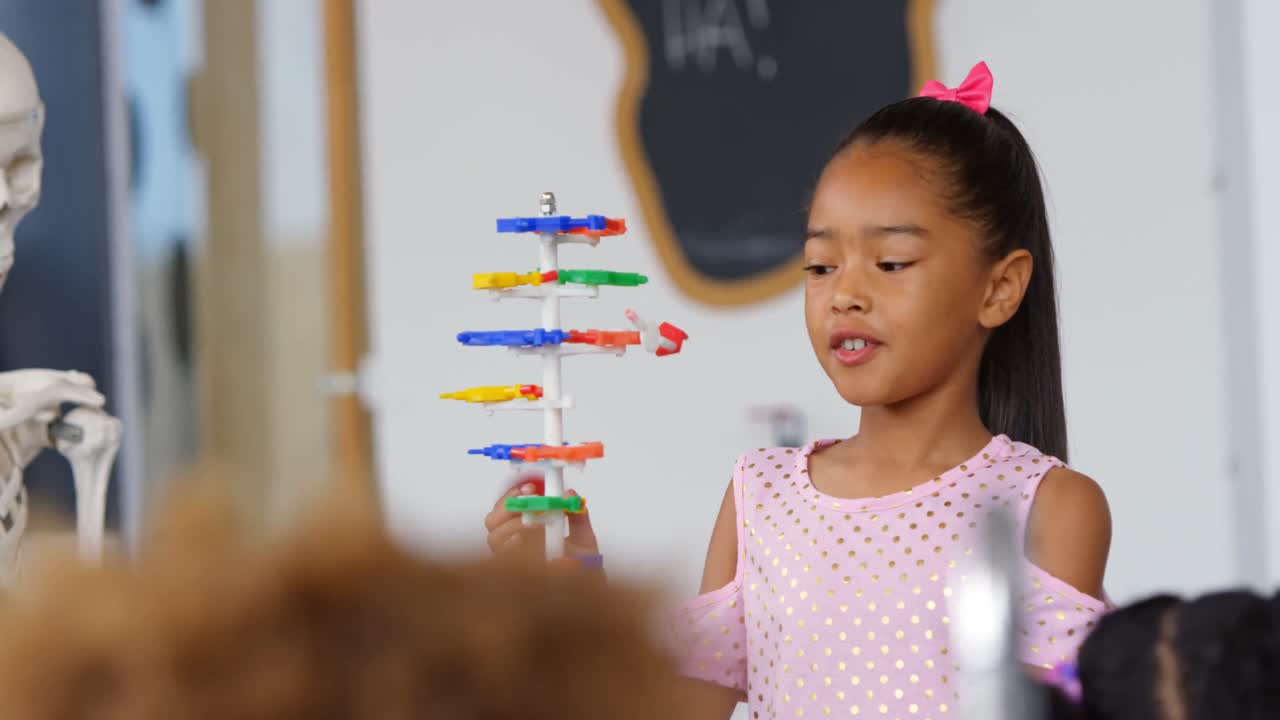 vista frontal de una colegiala asiática explicando sobre el modelo de estructura de adn en el aula 4k