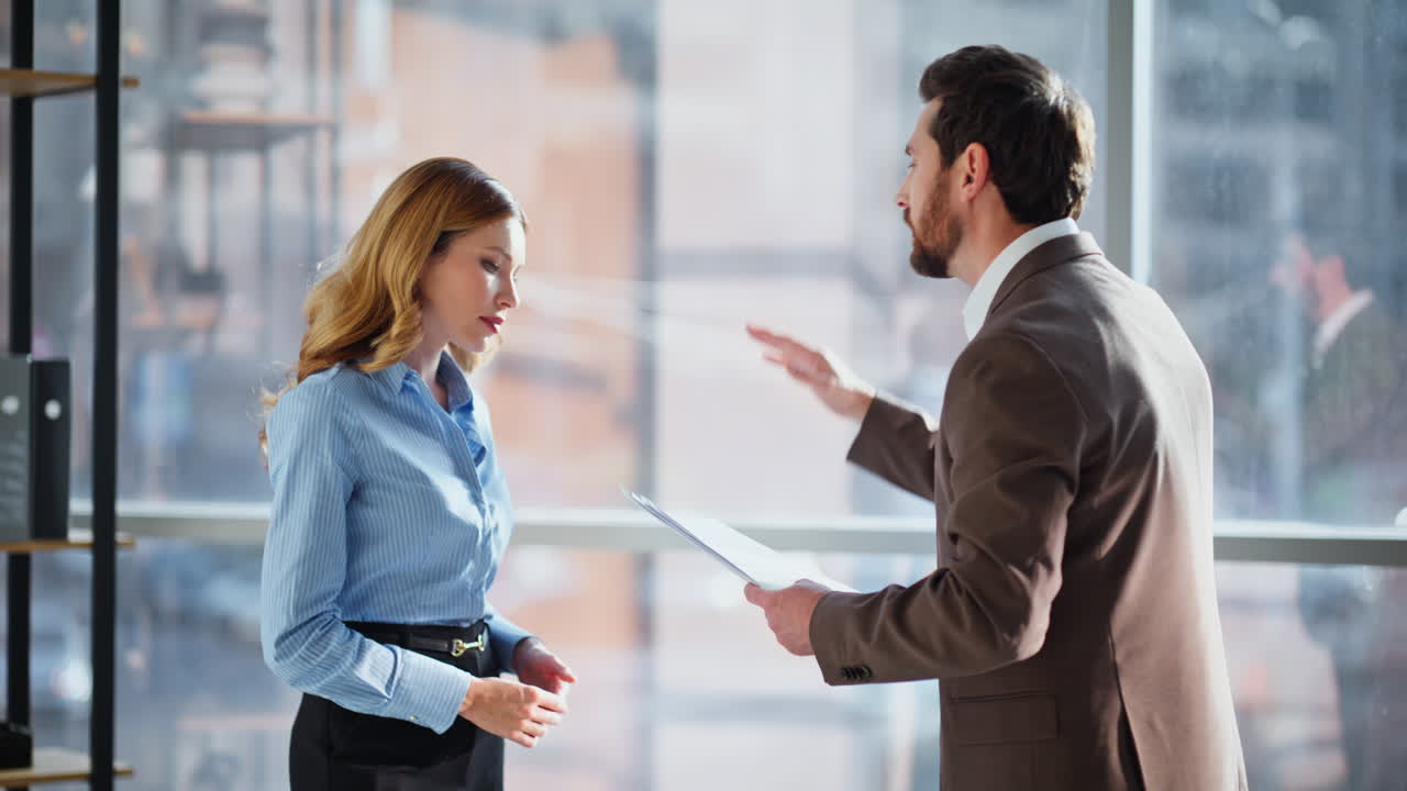 Dirigente arrabbiato che rimprovera il manager lamentandosi di un errore, in piedi in ufficio, primo piano.