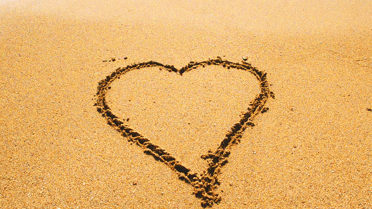 Cuore disegnato sulla sabbia. Riprese in spiaggia