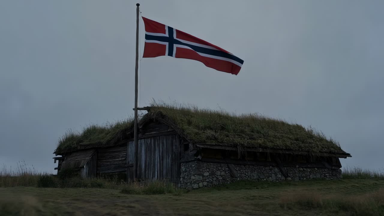 Det norske flagget vaier over en torvtakbygning på en gresslette i vindkastene