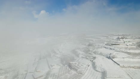 Vista-Aérea-Tirando-Hacia-Atrás-Del-Pueblo-Y-Las-Tierras-De-Cultivo-En-Terrazas-Después-De-La-Tormenta-De-Nieve,-Israel