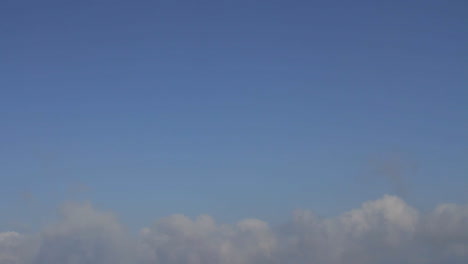 tilt down from a blue sky to the volcanic island of nea kameni in the middle of the santorini caldera