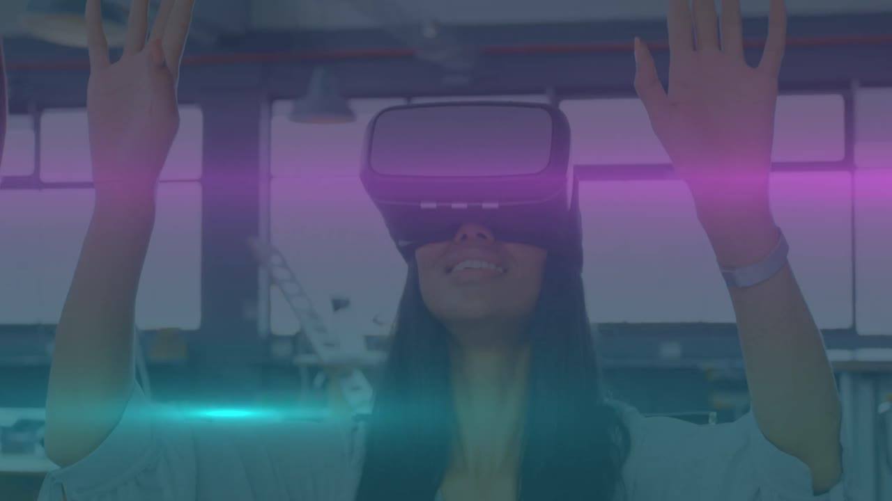 animación de rastros de luz azul y rosa moviéndose sobre mujer biracial usando auriculares vr en la oficina