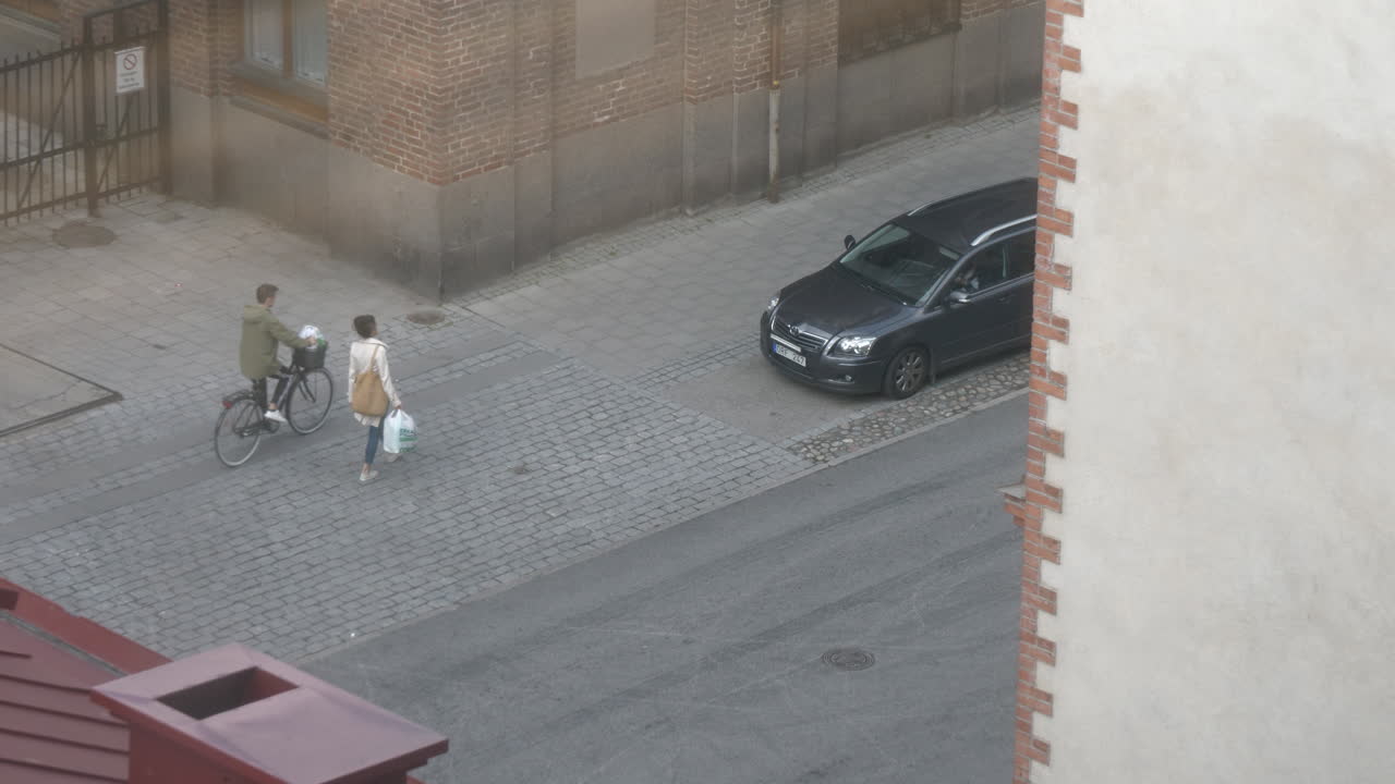 два человека, один идет, другой едет на велосипеде по булыжной мостовой тротуара, edi 10-bit готов к градации