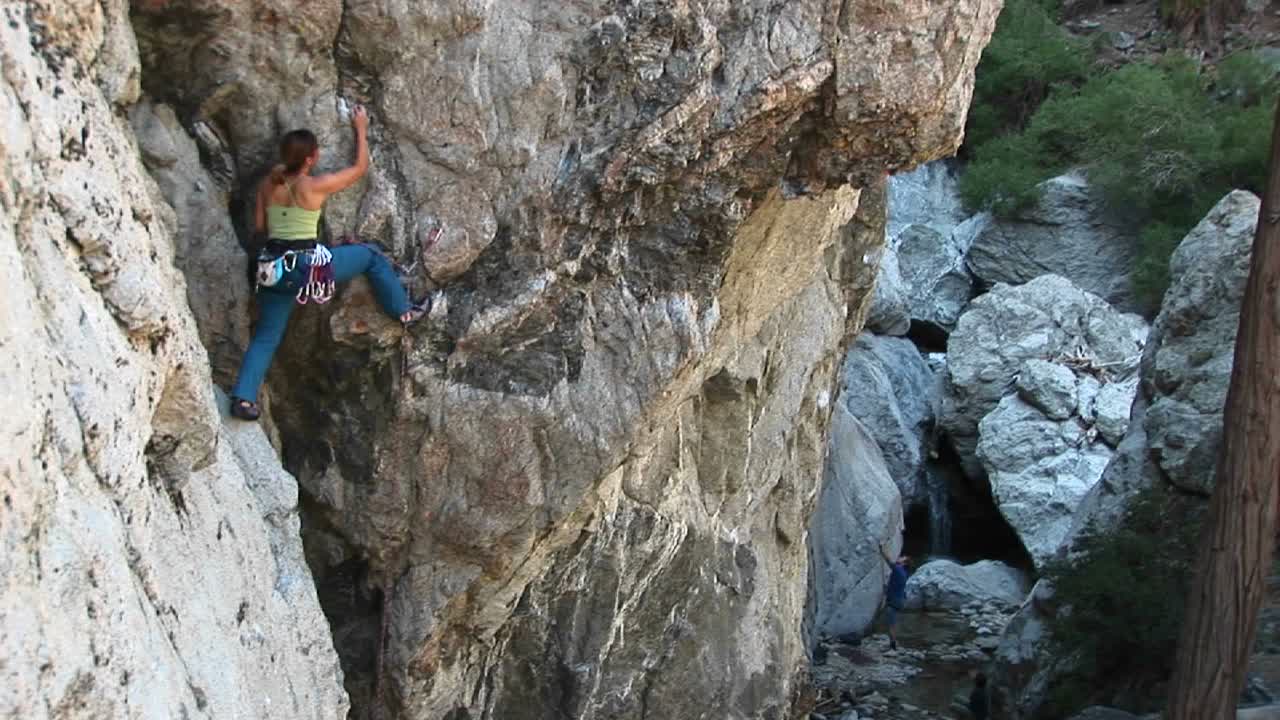 tiro largo de un escalador reorganizando sus mosquetones para escalar la pared de un acantilado