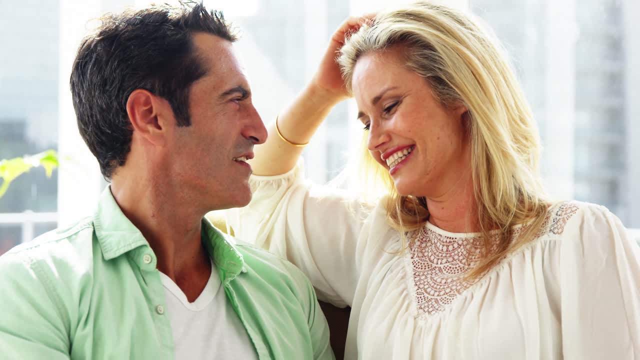 una joven pareja sonriente abrazándose en la sala de estar