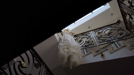 bridal gown hanging on a staircase with wrought iron balustrade