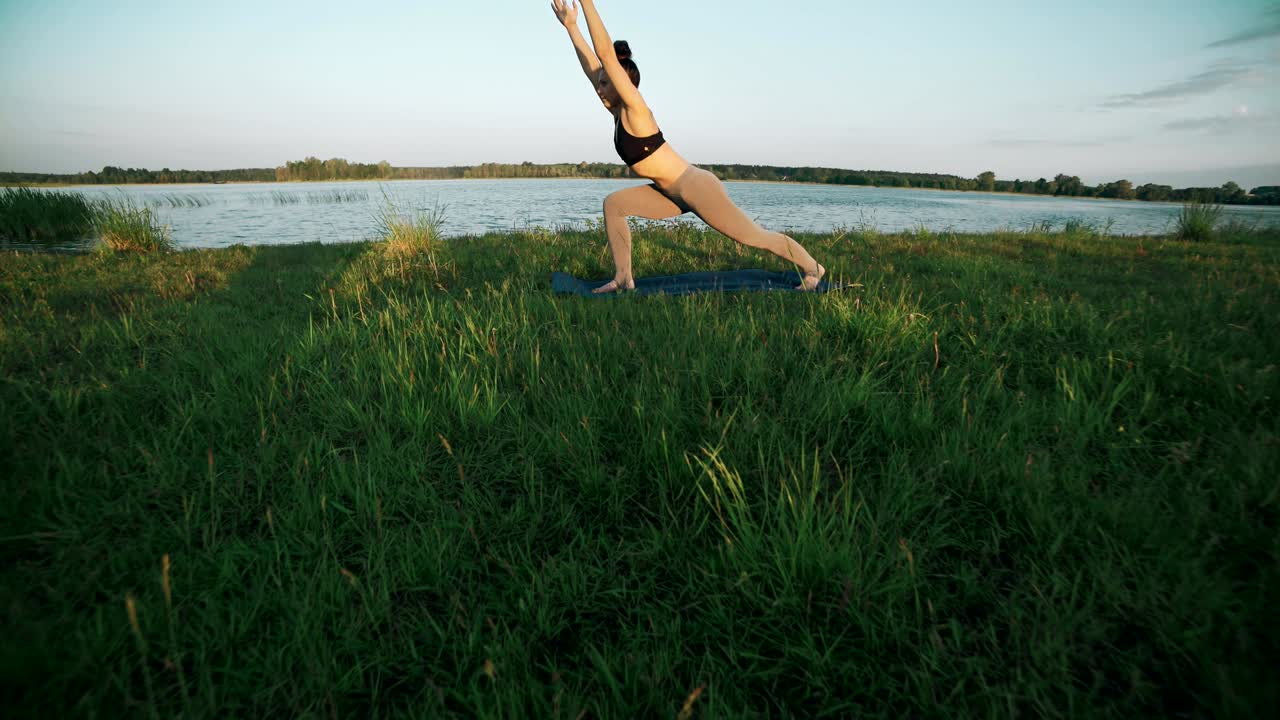 joven haciendo yoga se mueve en la hierba verde. mujer practicando yoga por la mañana