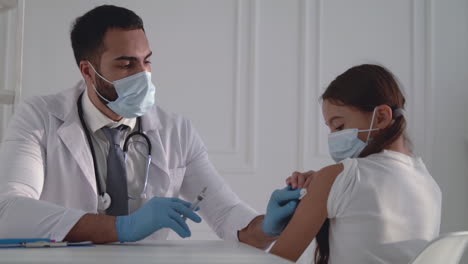 un médico masculino administrando una vacuna contra la covid-19 a una niña. un hombre dando una inyección para el coronavirus.