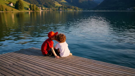 two children sharing a moment on a wooden pier by a calm lake