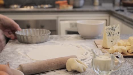 crop chef sprinkling quiche pan with flour while cooking