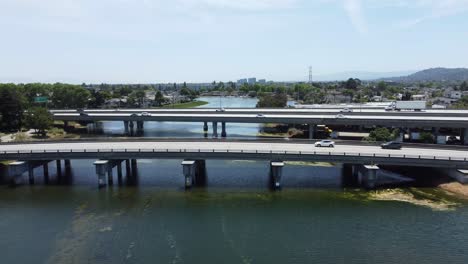 overtake shot of two bridges busy with cars crossing over beautiful long lagoon, san mateo, california