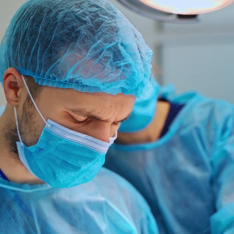 portrait of doctor in blue mask looking down. experienced surgeons saving patient's life in the operating room. close-up.