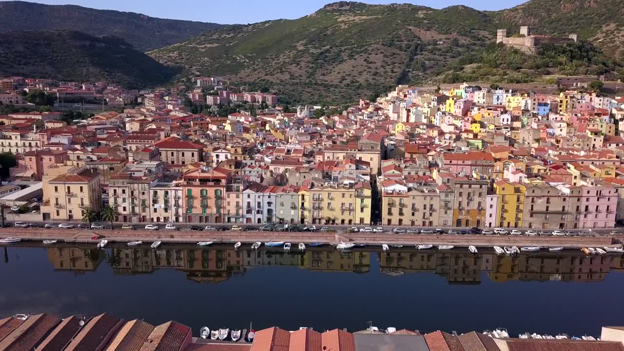 Bosa, Sardegna, Italia - Ripresa aerea con drone che si muove verso sinistra sopra il fiume Temo di fronte alla colorata città di Bosa