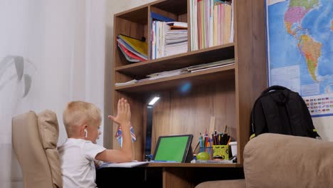 a small schoolboy boy is engaged with a teacher online, distance learning.