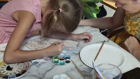 mother and daughter painting pottery