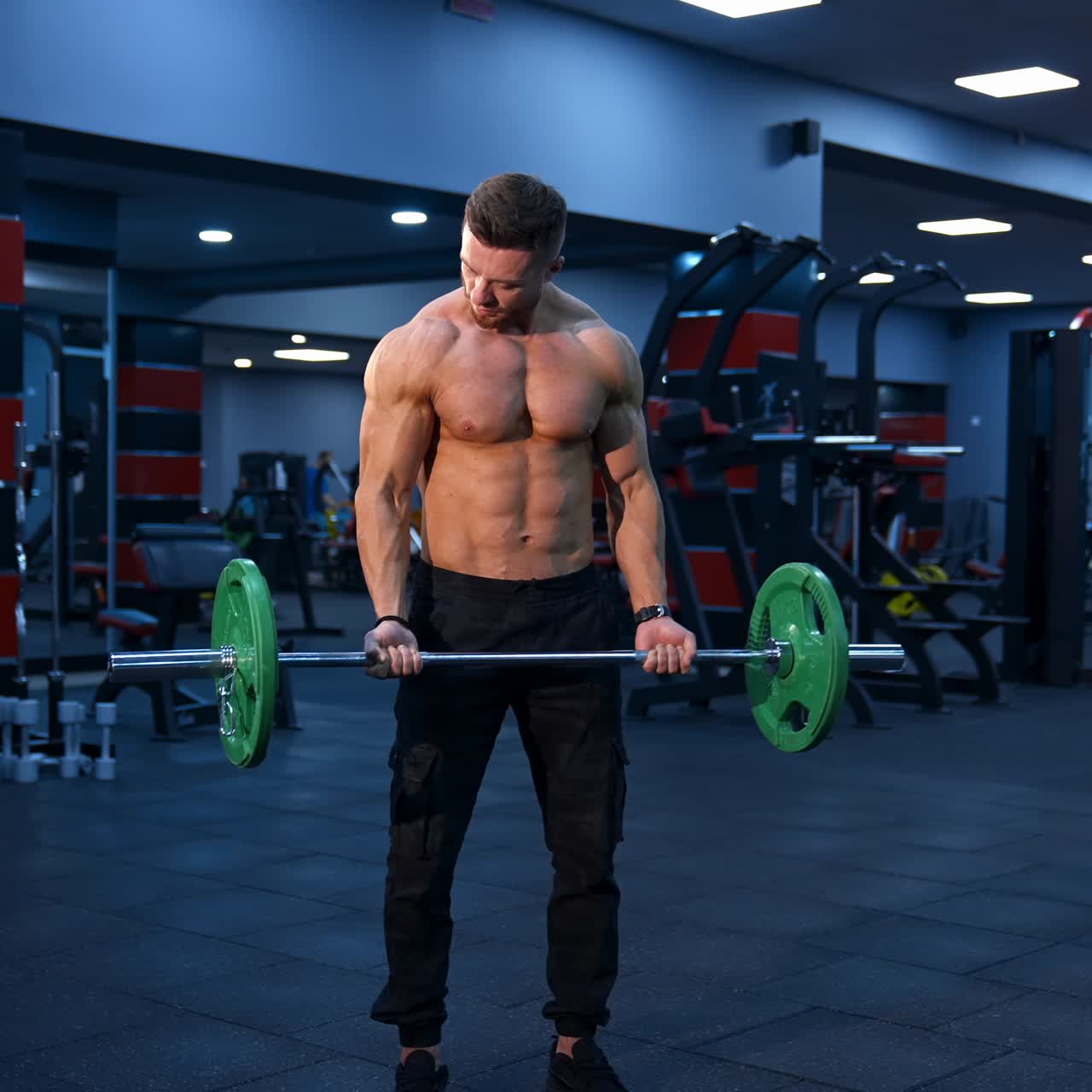 Athletic man in gym exercising with barbell. Bodybuilder with perfect body. Naked torso with perfect abs