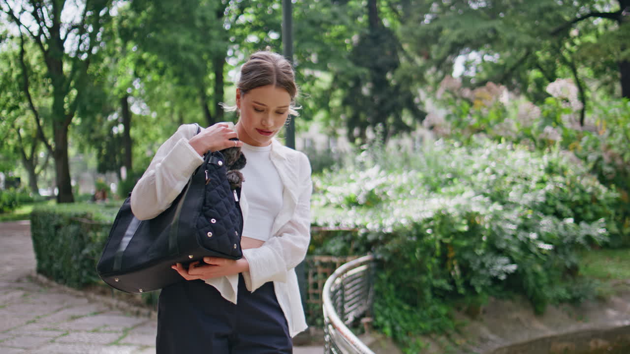 Joyful woman carrying dog walking green park closeup. Relaxed brunette smiling