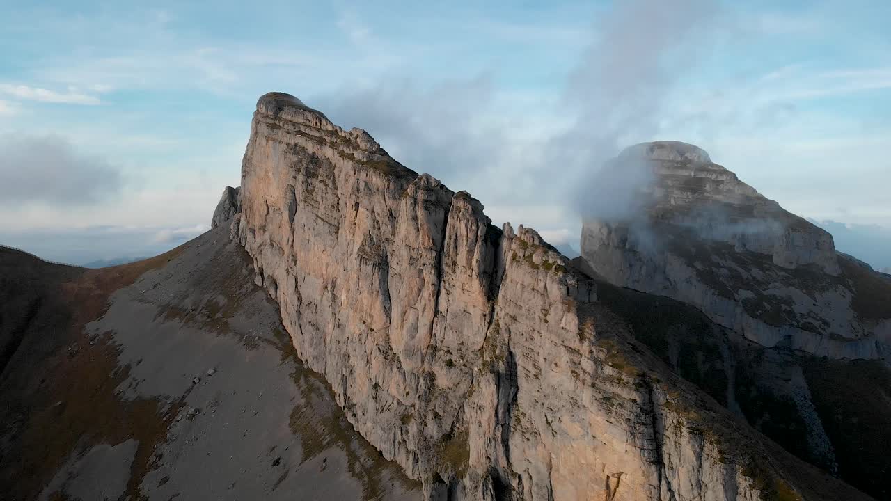 Aerial flyover alongside the cliffs of Tour d'A&iuml; in Leysin, Vaud, Switzerland with Tour de Mayen in view during a colorful autumn afternoon in the Swiss Alps