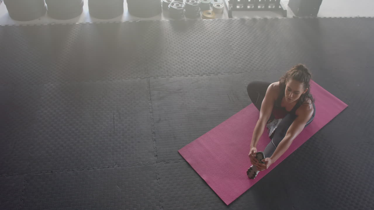 Stretching on yoga mat, strong fit woman exercising in gym, focusing on flexibility, copy space